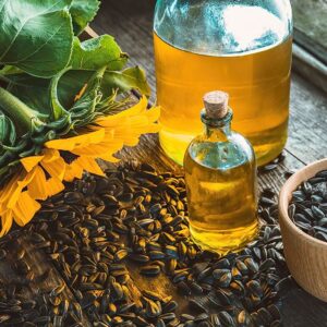 Black oil sunflower seeds scattered on table with a bottle of sunflower oil