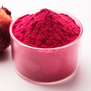 Natural beetroot dye powder inside a glass dish next to fresh beetroot