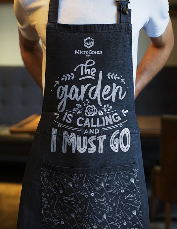 Man wearing a black microgreen silo themed gardening apron